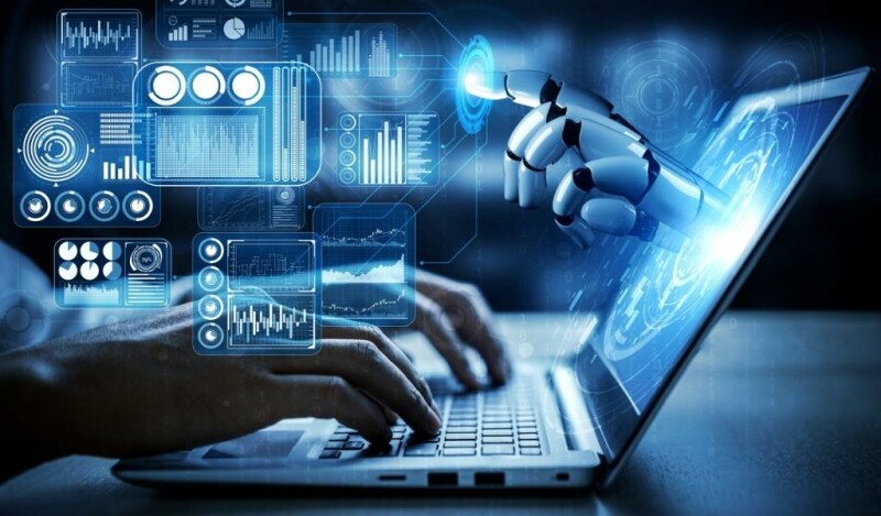 Person working on laptop with artificial intelligence or robot hand reaches out pointing to abstract technology designs
