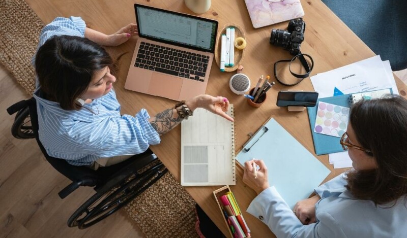 Coworkers collaborating using a laptop and paper