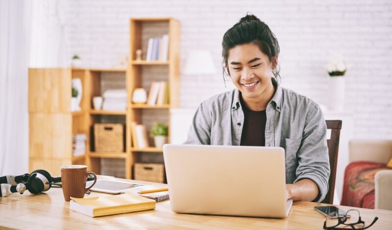 Man working from home and smiling at laptop