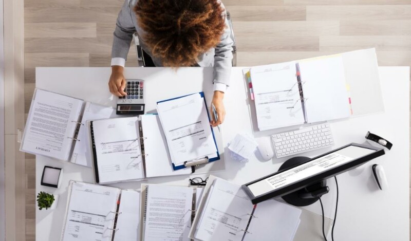 Woman working at a desk filled with different papers and a computer