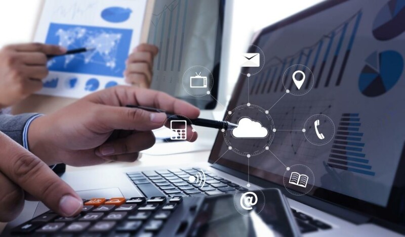 Person gesturing toward computer screen with a pen with imagery of a digital icons including: cloud, mail, phone, pin, calculator, cash, and briefcase