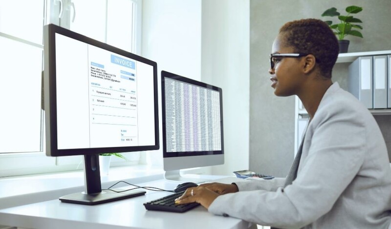 Woman facing her computer screens that contain information on invoices