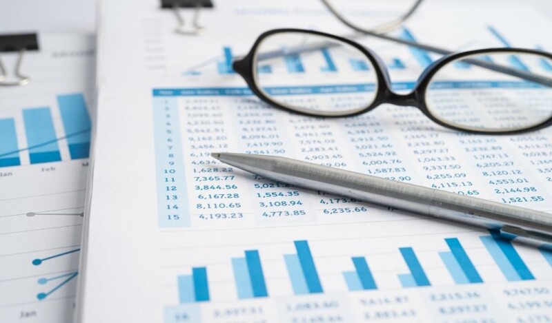 Glasses and a pen sitting on top of a paper with a chart of numbers and a bar graph on it