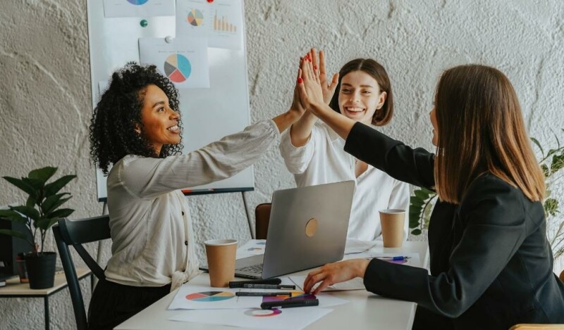 A team of 3 women working together on a project and high-fiving