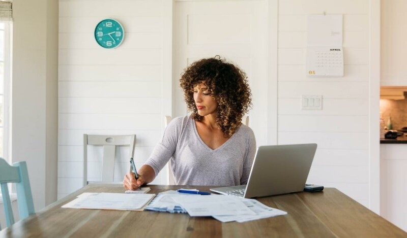Woman working from home with her laptop open while taking notes