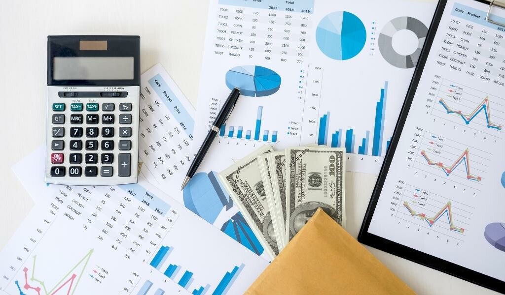 Assortment of work documents, a pen, calculator, and cash