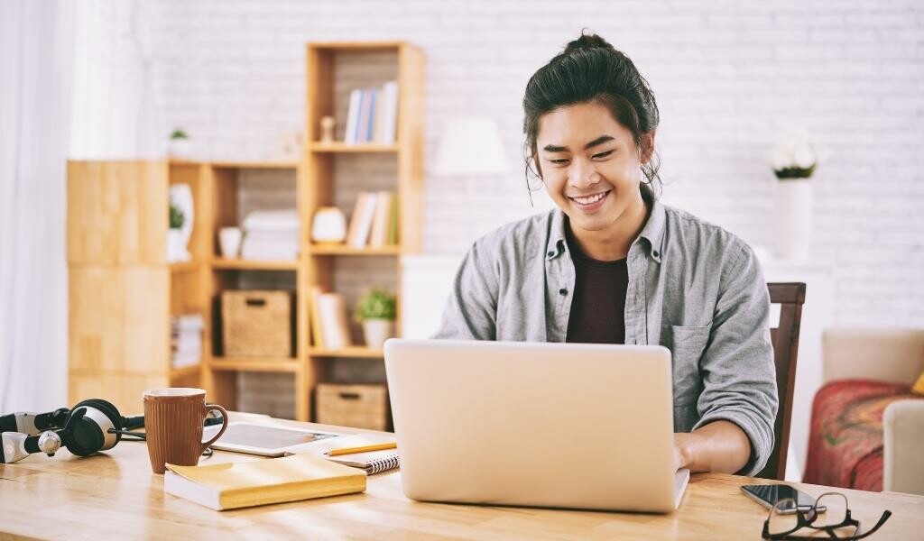 Man working from home and smiling at laptop