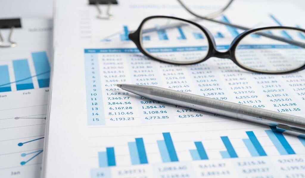 Glasses and a pen sitting on top of a paper with a chart of numbers and a bar graph on it