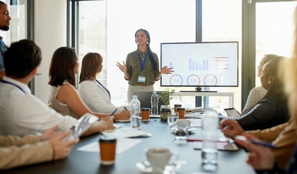 Woman giving a presentation to her table of coworkers