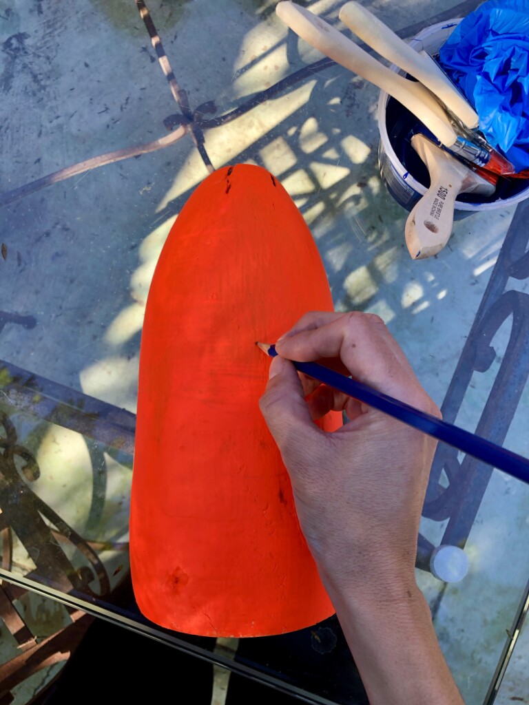 Drawing on an orange buoy with a pencil.