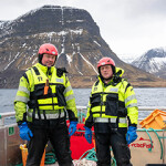 Two workers with Arctic Fish standing by the ocean.