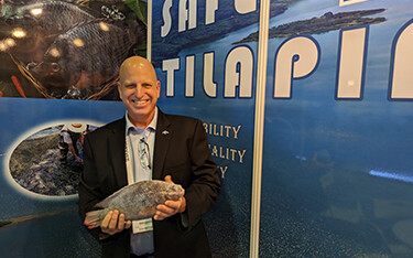 Ron Risher posing with one of the company's tilapia during Seafood Expo Asia