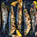Sardines on a grill with lemon slices.