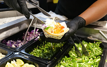 An Aramark Collegiate Hospitality employee serving food.