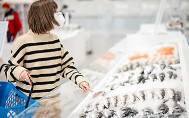 A woman shopping for seafood at a grocery store.