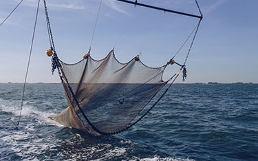 A fishing boat towing a net for bottom trawling.