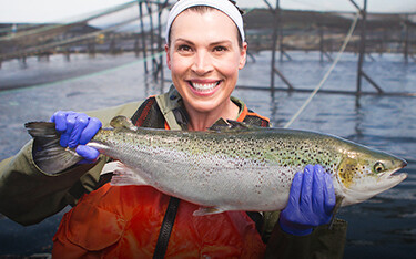 A Cooke employee with a farmed salmon.