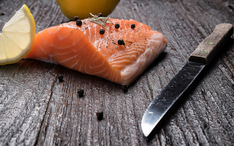 Norwegian salmon on a counter with a lemon and a knife.