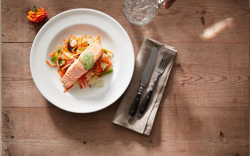 A piece of salmon on a plate on a wooden table.