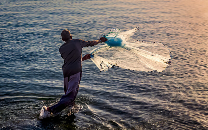 A fishermen throwing fishing net during sunrise