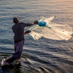 A fishermen throwing fishing net during sunrise