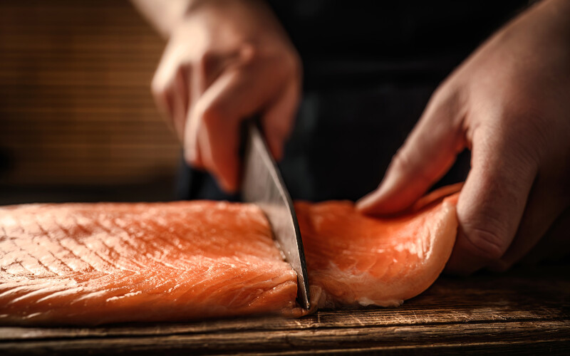 A chef cutting a fillet of salmon