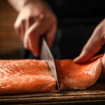 A chef cutting a fillet of salmon