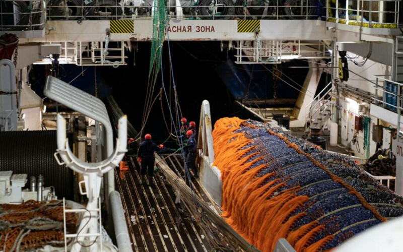 Workers on a Russian fishing vessel pull in a net