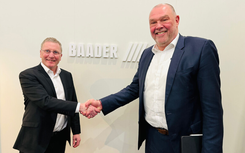 Grieg Director Piotr Wingaard and BAADER Norway Vice President of Sales Modulf Barstad shake hands at BAADER's booth in Barcelona, Spain