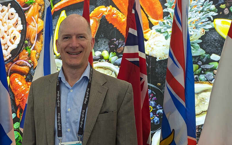IFCA Chair Paul Lansbergen in front of a background of flags
