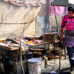 A Uyghur man grills fish at the Yopurga weekly market near Kashgar in China's Xinjiang Uyghur Autonomous Region
